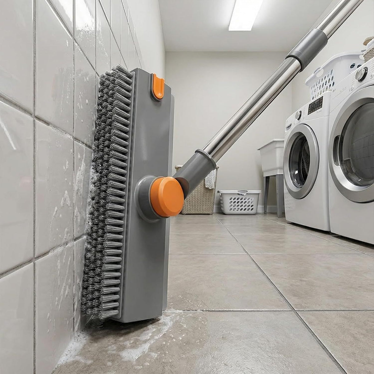Cleaning tool with orange bristles being used on a tiled floor in a laundry room.