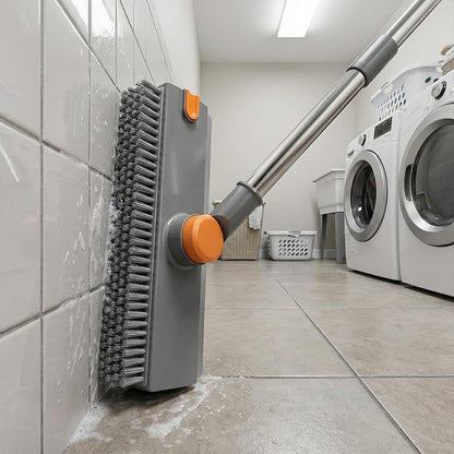Cleaning tool with orange bristles being used on a tiled floor in a laundry room.